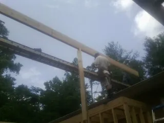 Carpenter setting a ridge beam over a new addition frame — Ice Dam Removal by Roofing Brothers in Ottine