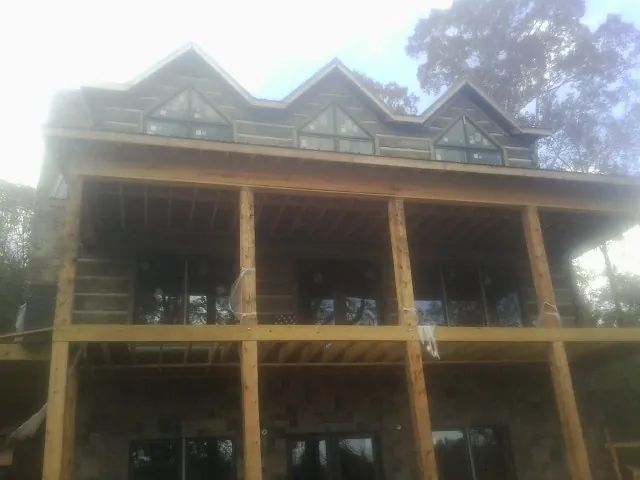 Dormers and porch framing on a large log home under construction — Roof Coating work by our crew in Ottine