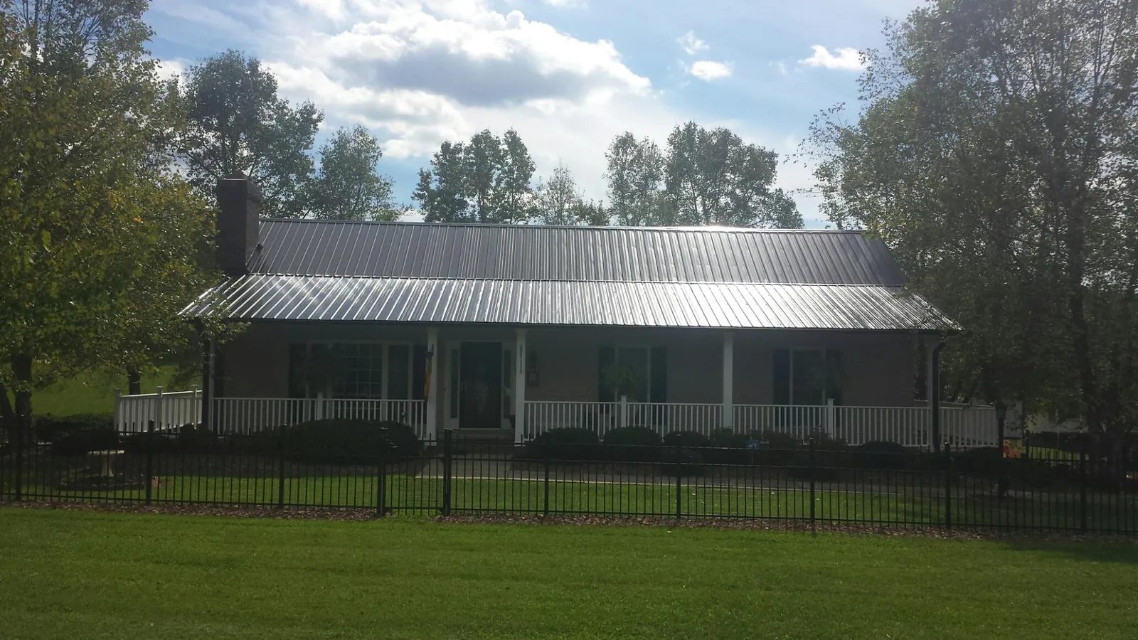 Gray metal roof on a brick ranch with a full width front porch — Gutter Guard Installation work by our crew in Ottine