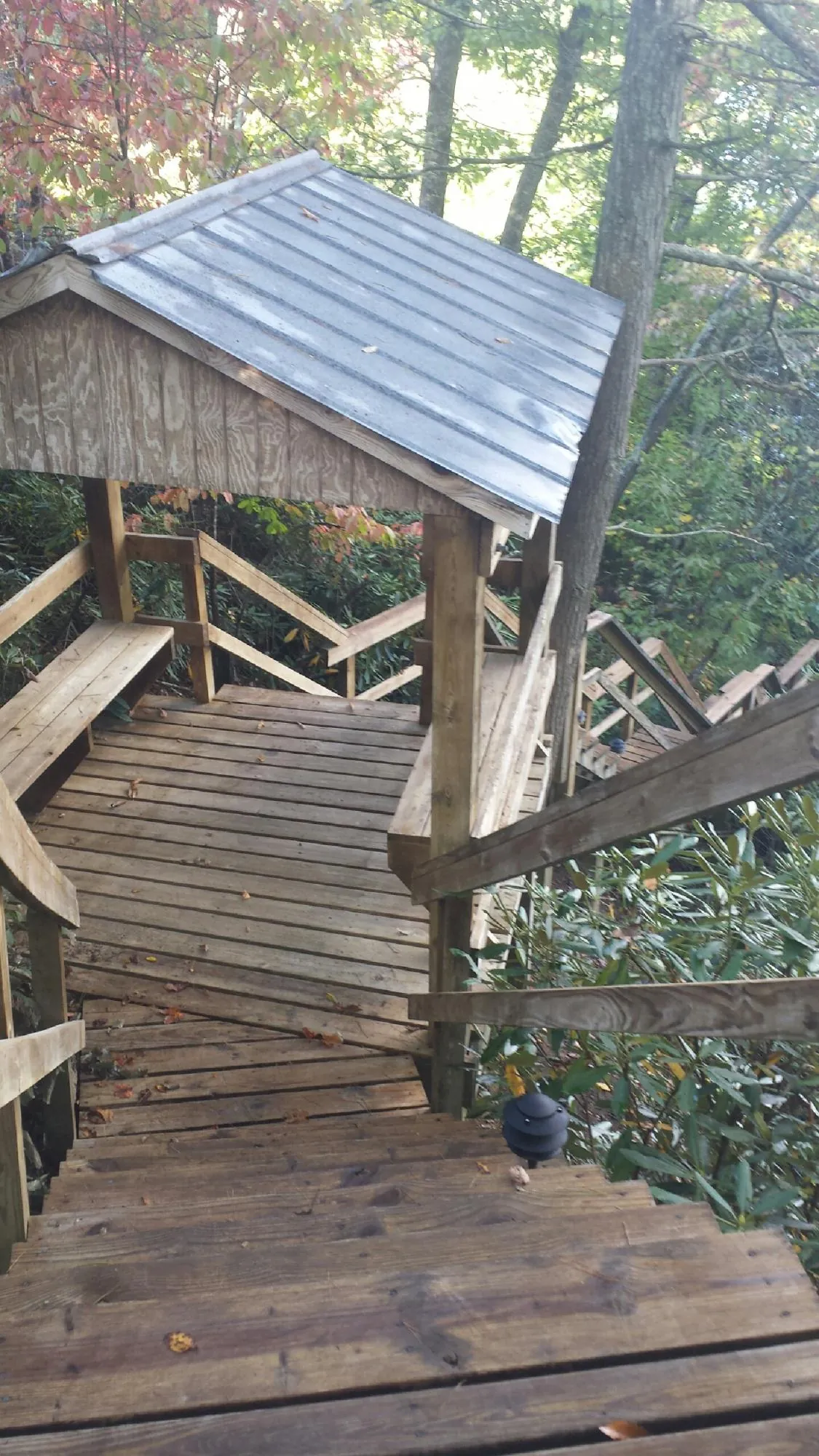 Metal roofed shelter over wooden steps on a wooded walkway — Skylight Repair & Installation work by our crew in Ottine