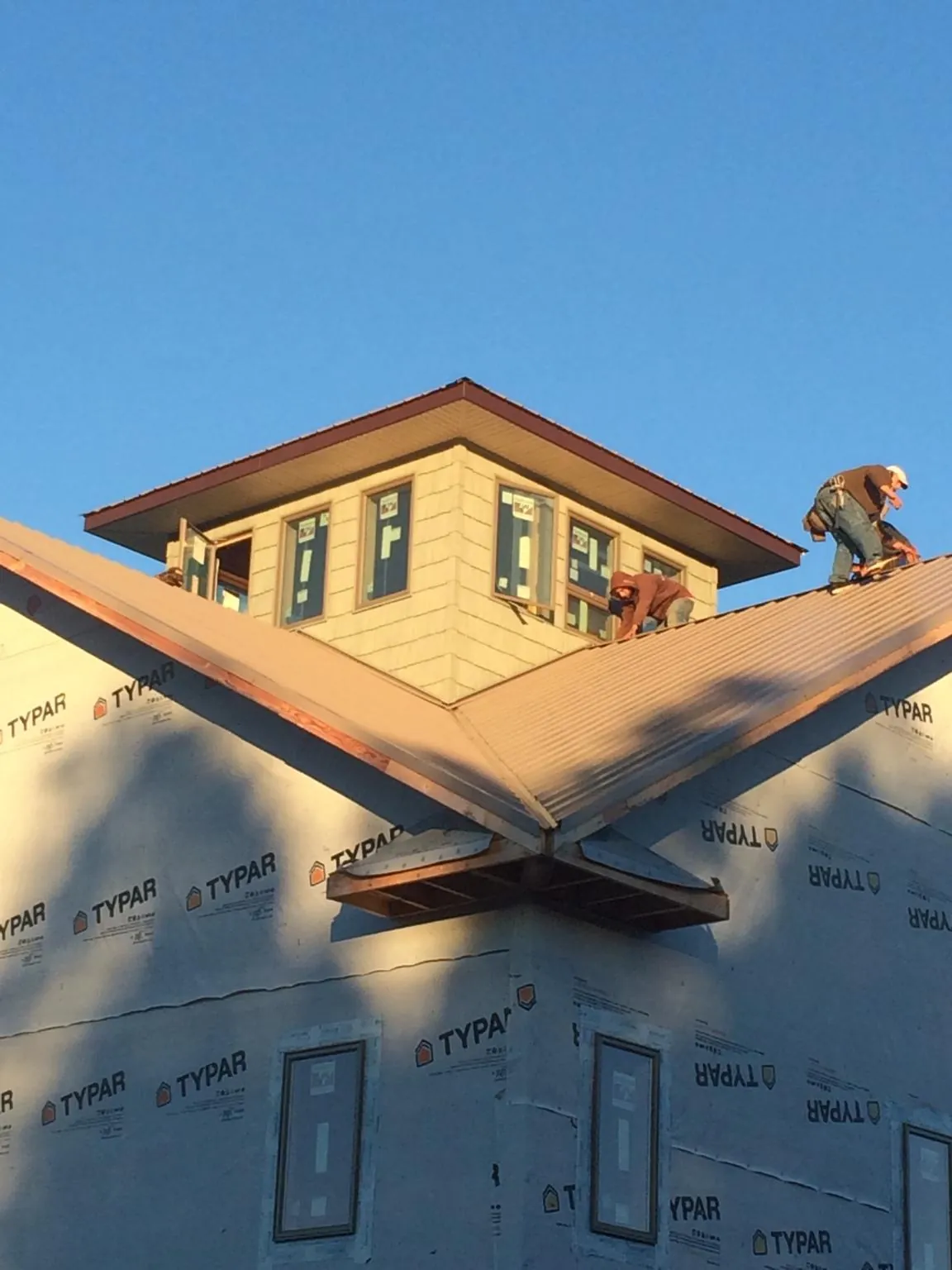 Roofers working around a rooftop cupola on a new metal roof at sunset — Roof Waterproofing in Ottine by Roofing Brothers